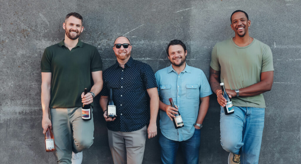 The Chosen Family Wines team standing in front of a wall holding wine bottles